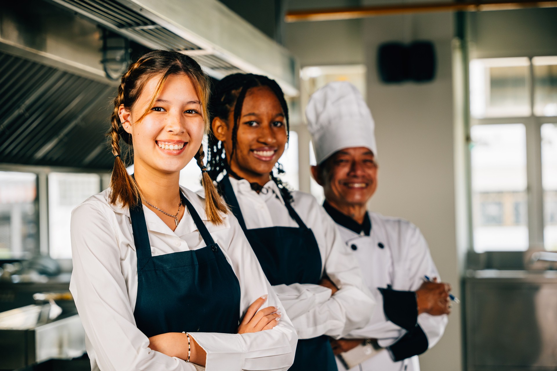 Chefs in uniform smiling at the camera in a professional kitchen. Illustrating expertise teamwork and togetherness. Teaching and learning in action.